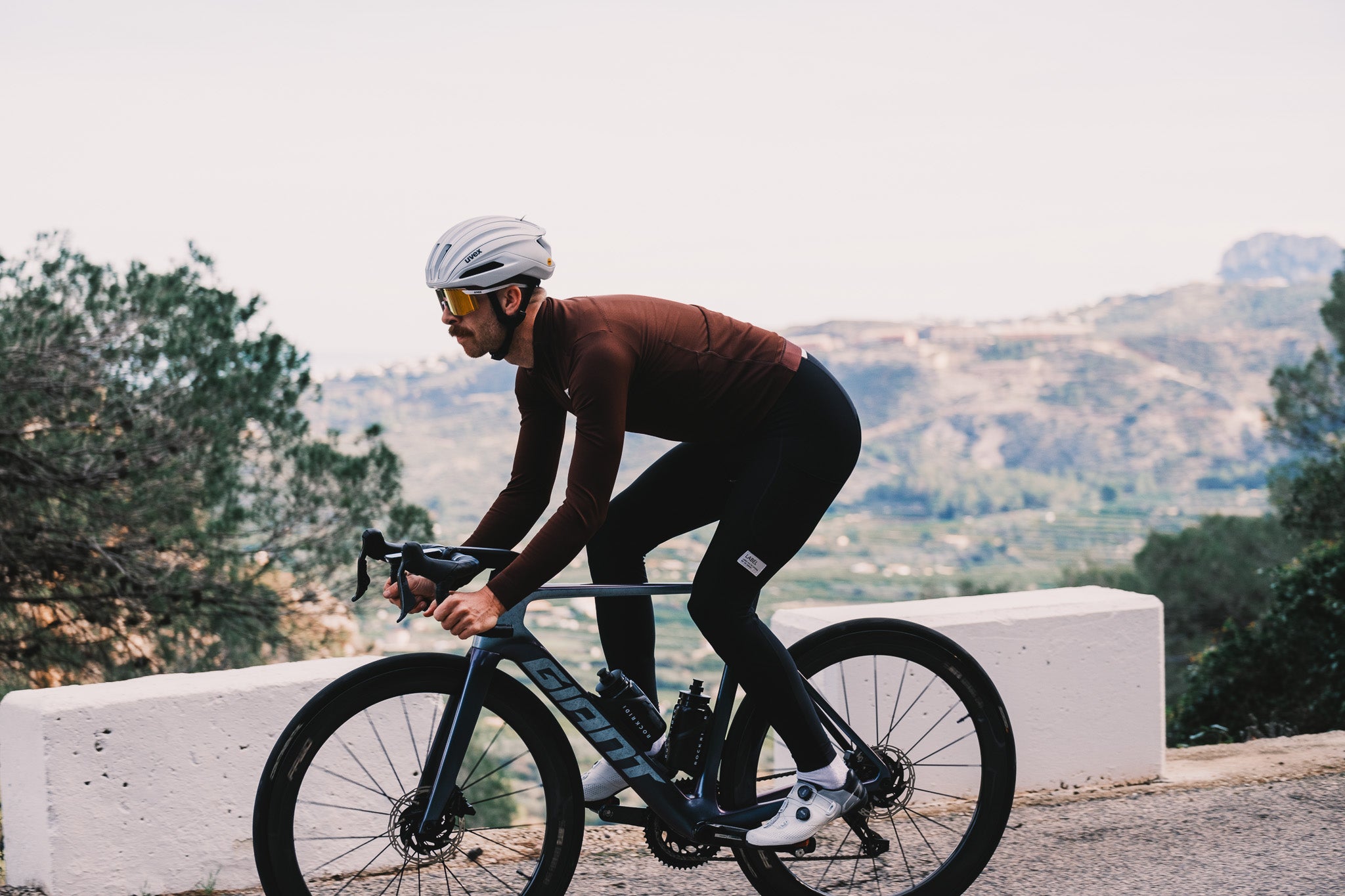 Cycling in Alicante in Label Collective Thermal Jersey in brown on a giant road bike. 